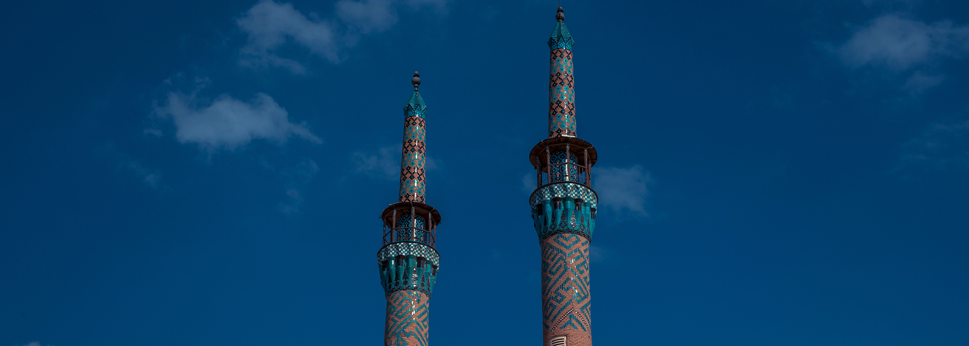 twin minarets of Amir Chakhmaq Mosque in yazd, iran. set agains a clear blue sky.