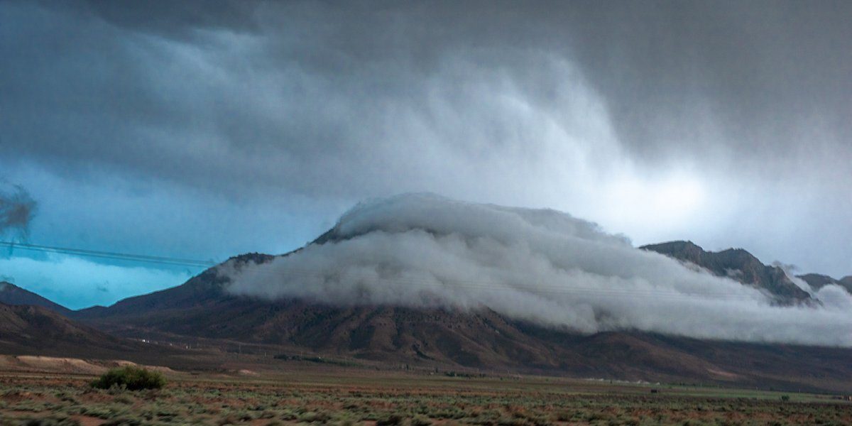 A solitary mountain wrapped in clouds under a dramatic, dark sky along the Damghan to Kiasar route.