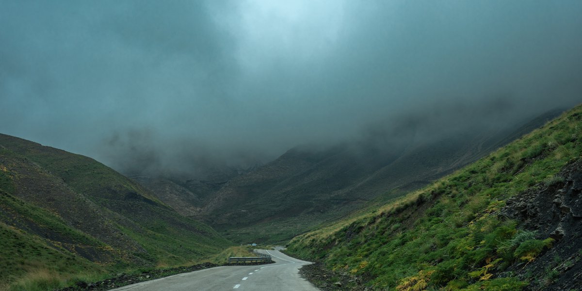 Final section of the road to Yush village with dense forest and descending fog