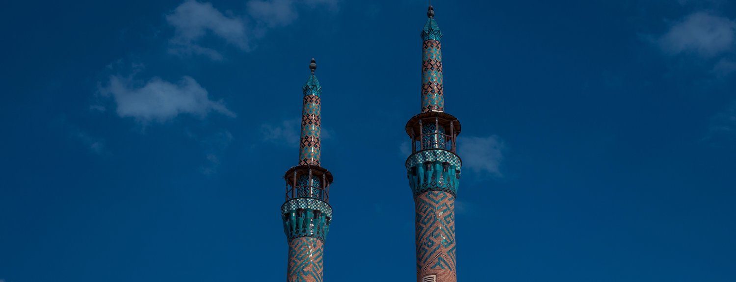 twin minarets of Amir Chakhmaq Mosque in yazd, iran. set agains a clear blue sky.